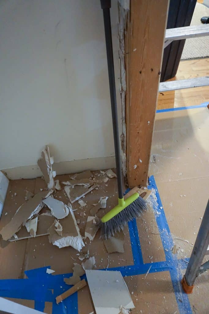 Dirty floor covered in cardboard with drywall and blue painters tape 
