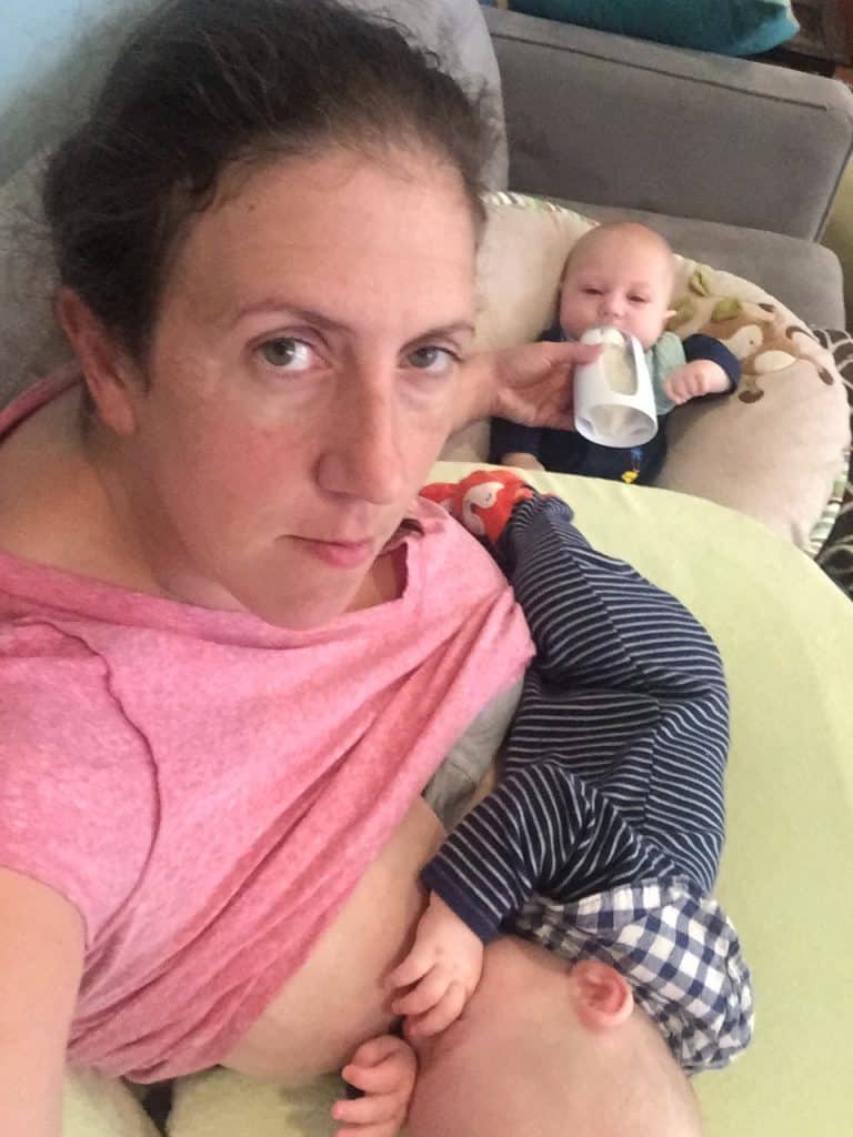 Mom nurses one twin while bottle feeding another.
