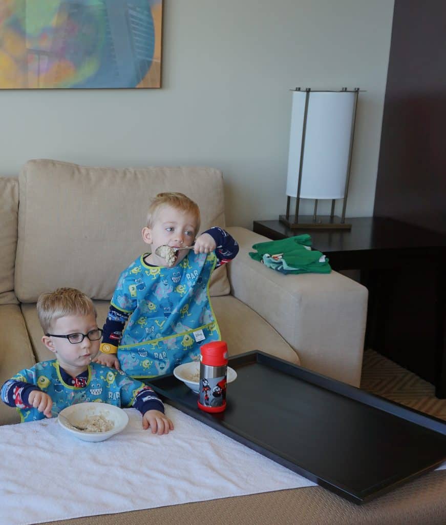 Twin toddler boys at Disney Contemporary Resort eating oatmeal wearing Bumpkins Junior bibs