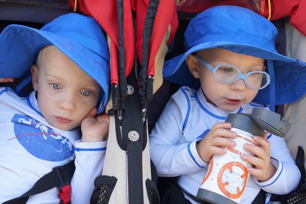 Twin toddlers in NAsa shirts and blue hats in a BOB strollder