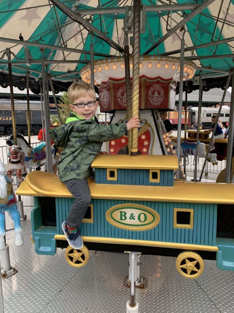 At A day out with Thomas a happy toddler rides a B&O Railroad boxcar on a merry go round wearing Dilli Dalli Eyeglasses