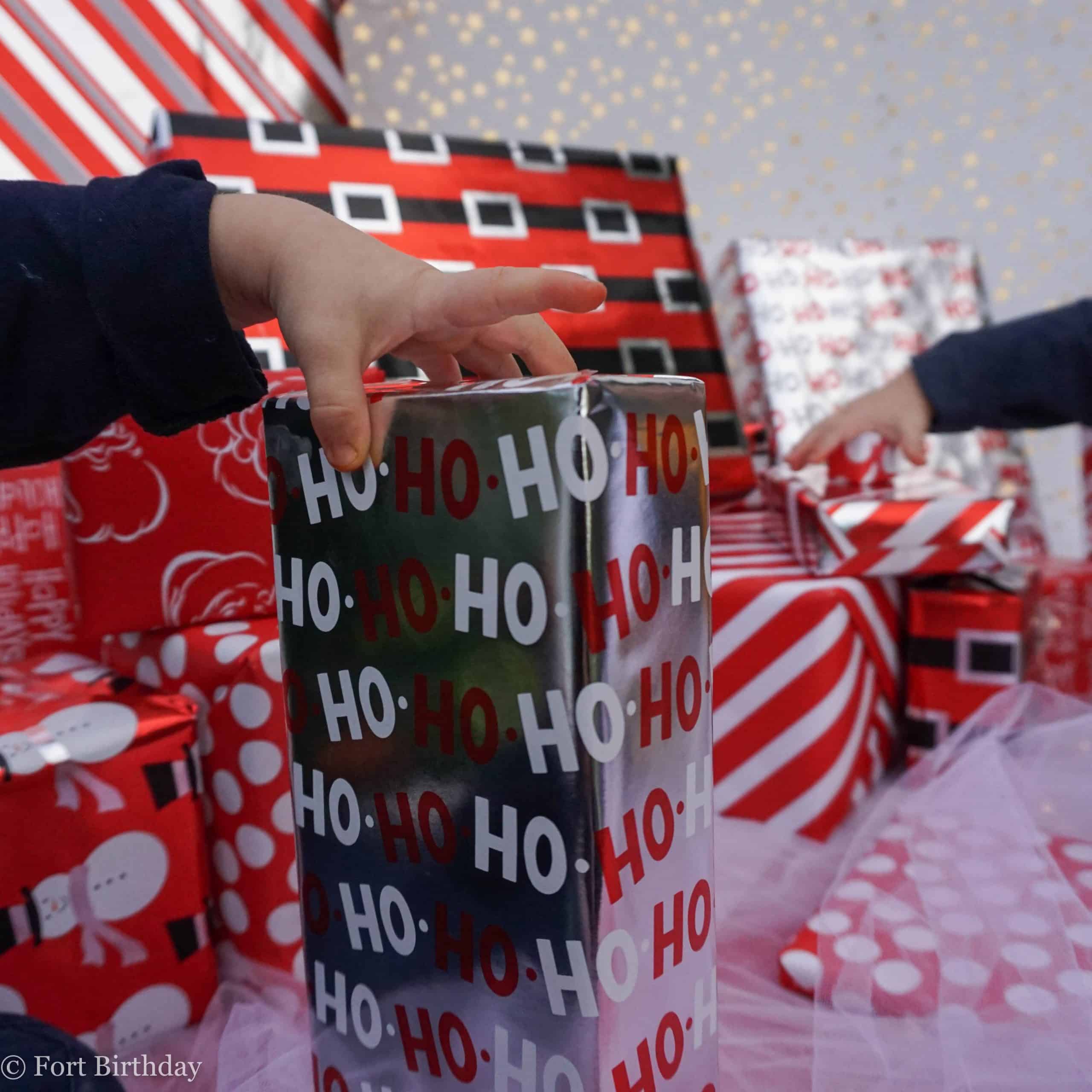 Toddler hands reach for gifts wrapped in red and silver paper