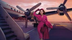 the Marvelous Mrs. Maisel walking towards an airplane in an amazing pink dress.